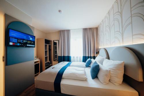 a hotel room with a bed and a television at guestified LIYANA in Ratingen
