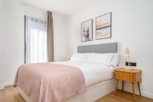 a white bedroom with a large bed and a window at Limehome Barcelona Plaça Pirineus in Hospitalet de Llobregat