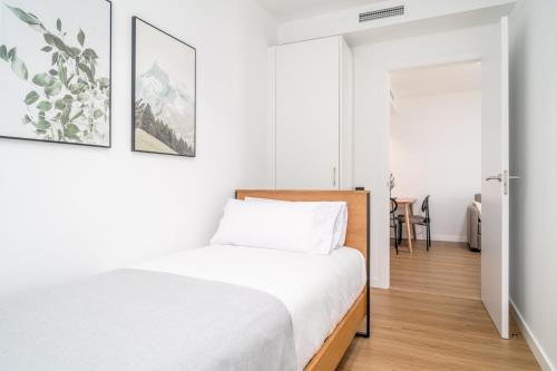 a white bedroom with a bed and a table at Limehome Barcelona Plaça Pirineus in Hospitalet de Llobregat