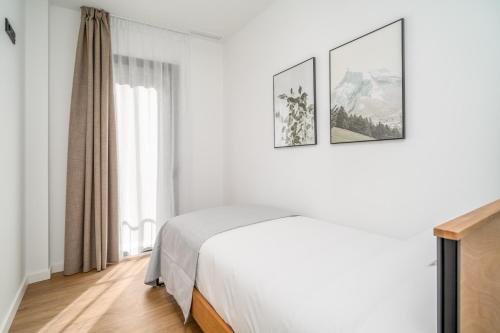 a bedroom with a bed and two pictures on the wall at Limehome Barcelona Plaça Pirineus in Hospitalet de Llobregat