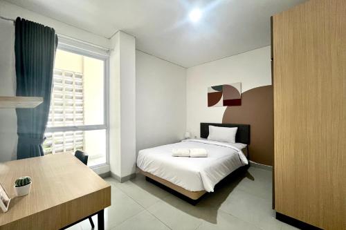a white bedroom with a bed and a window at Cove Nawaprita in Jakarta