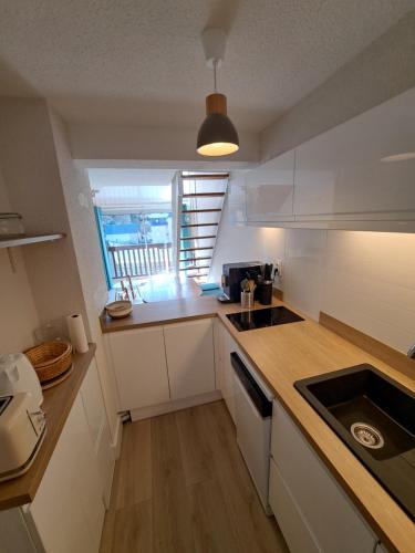 Elle comprend une petite cuisine avec des placards blancs et une fenêtre. dans l'établissement Appart Duplex 4/5p - Saint-Lary, à Saint-Lary-Soulan