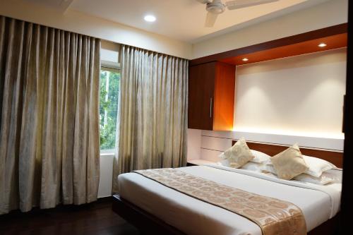 1 dormitorio con 1 cama grande y ventana en Chola Serviced Apartment, en Tiruchchirāppalli