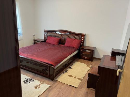 um quarto com uma cama com lençóis vermelhos e almofadas vermelhas em Apartment në qendër të Gjilanit em Gjilan
