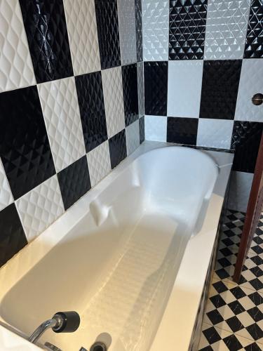 a bath tub in a bathroom with black and white tiles at Nico's Hotel 2 in Siem Reap