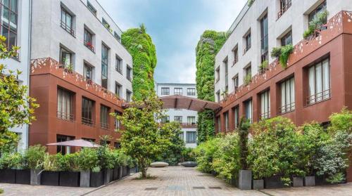 une cour de bâtiments avec des plantes et des arbres dans l'établissement Superbe Loft 67 m2 Bastille Marais, à Paris