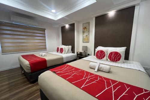 a hotel room with two beds with red and white at Khotel Pasay in Manila