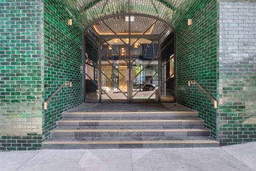 an entrance to a building with a green brick wall and stairs at Greenhouse Apartments by Urban Rest in Auckland