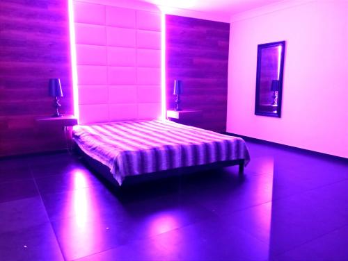 a bedroom with a bed with purple lights on it at Private Luxury Club in Poznań