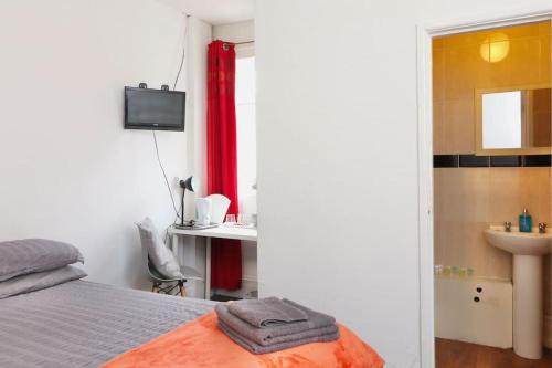 a bedroom with a bed and a bathroom with a sink at Pebbles guest house in Southampton