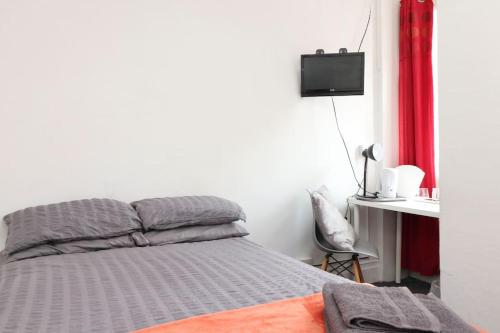 1 dormitorio con 1 cama y escritorio con TV en Pebbles guest house, en Southampton