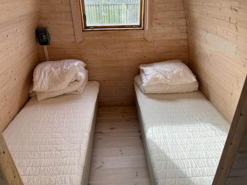 two beds in a small room with a window at Camping Vesterhav in Harboør