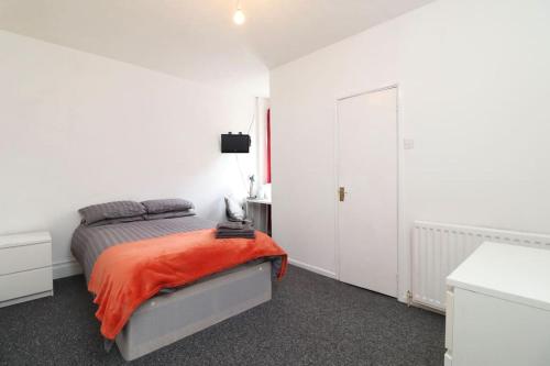 a white bedroom with a bed with an orange blanket at Pebbles guest house in Southampton