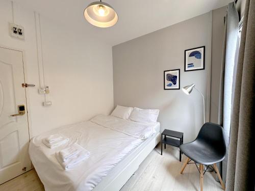 a small bedroom with a white bed and a chair at Na Ekkamai Residence in Bangkok