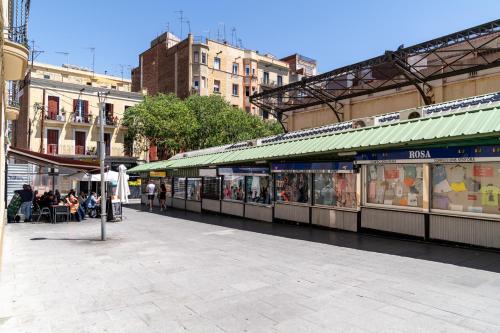 a street with people sitting outside of a store at Limehome Barcelona Plaça Pirineus in Hospitalet de Llobregat