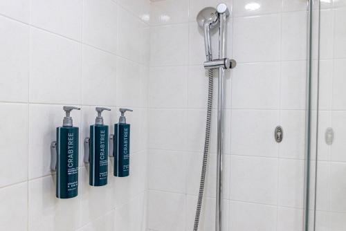 prysznic z trzema niebieskimi butelkami na ścianie w obiekcie Hilton Odawara Resort & Spa w mieście Odawara
