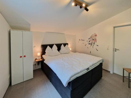 ein Schlafzimmer mit einem großen Bett mit weißer Bettwäsche in der Unterkunft Waldhaus Tiedtke in Wedemark