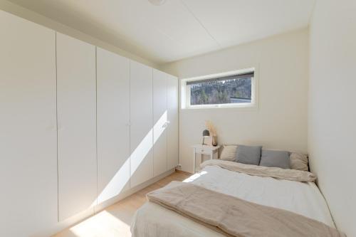 Habitación blanca con cama y ventana en Nydelig selveier leilighet med gratis parkering på stedet, en Alta