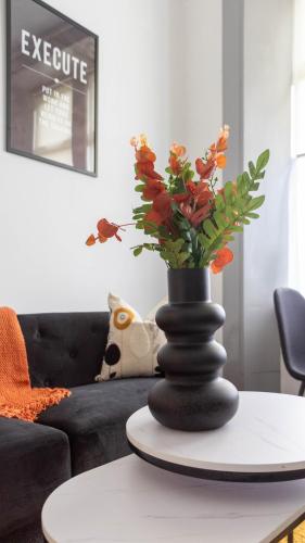 a black vase with flowers on a table in a living room at Castlegreen Apartment in Dumbarton