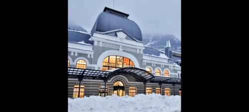 a building covered in snow with the lights on at Apartamento de montaña "Nueva Canfranc" in Canfranc-Estación