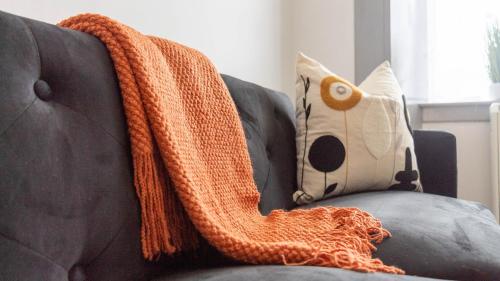 an orange knit blanket sitting on a couch at Castlegreen Apartment in Dumbarton