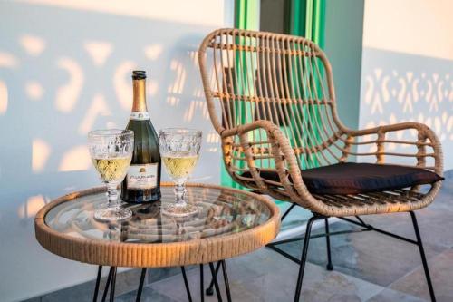 uma mesa de vidro com uma garrafa de vinho e dois copos em La Scala Luxury Villa Μikis Theodorakis with jacuzzi em Cárpatos