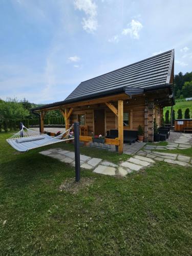 a log cabin with a hammock in front of it at Jodłowa Chata in Myślenice