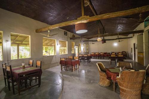 a restaurant with tables and chairs in a room at Bardia Riverside View Park Resort - FR and EN speaking in Bhurkīā
