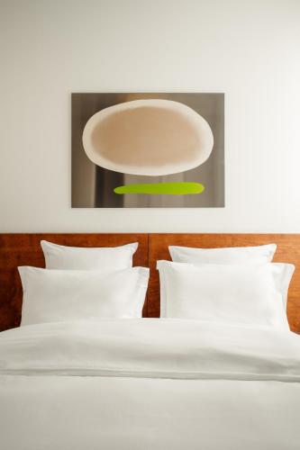 un lit avec des oreillers blancs et une assiette au-dessus dans l'établissement Edgar Suites Marais - Temple, à Paris