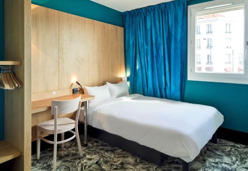 um quarto de hotel com uma cama, uma secretária e uma janela em B&B HOTEL Paris Porte de la Villette em Paris