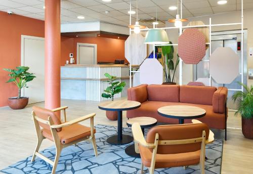 a lobby with a couch and two tables and chairs at B&B HOTEL Paris Porte de la Villette in Paris