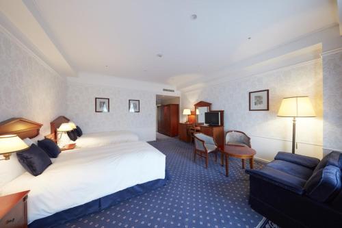 een hotelkamer met een groot bed en een bank bij Hotel Amsterdam Huis Ten Bosch in Sasebo