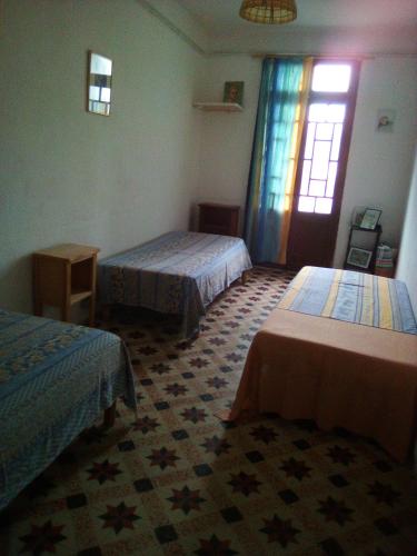 une chambre d'hôtel avec deux lits et une fenêtre dans l'établissement Ancien café des années 30, à Bélesta