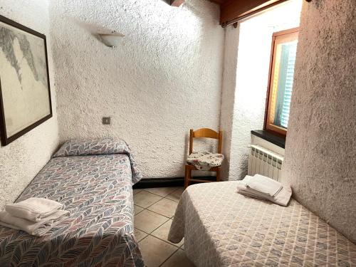 Habitación con 2 camas, silla y ventana en Appartamento Isola - In the center with Terrace - sea view & AC en Corniglia