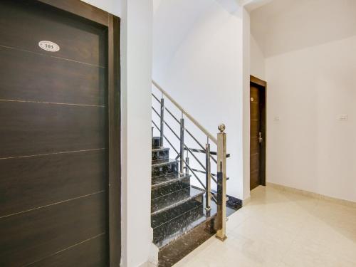 a hallway with a black door and stairs at The Nines Hotel & Restro in Kālādhūngi