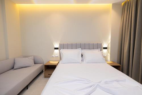 a bedroom with a white bed and a couch at Hotel Aluor in Vlorë