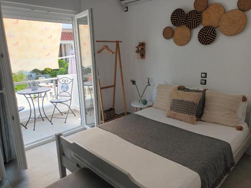 a bedroom with a bed and a balcony with a table at Maison Kalogiannis in Patitiri