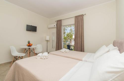 a bedroom with two beds and a table and a window at Dora's Apartments in Laganas