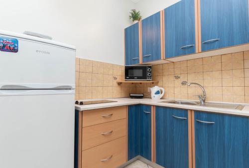 a kitchen with blue cabinets and a white refrigerator at Dora's Apartments in Laganas