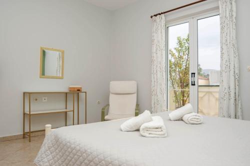 a white bedroom with a bed and a window at Dora's Apartments in Laganas