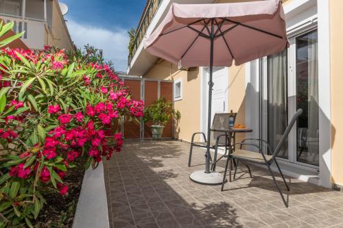 a patio with a table and an umbrella and flowers at Dora's Apartments in Laganas