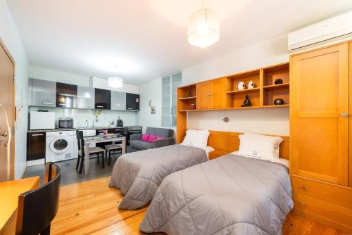 two beds in a room with a kitchen and a dining room at Casas da Alegria in Coimbra