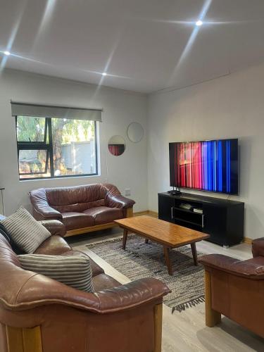 salon ze skórzanymi meblami i telewizorem z płaskim ekranem w obiekcie 2 Bedroom Apartment in Waverley, Bloemfontein w mieście Bloemfontein