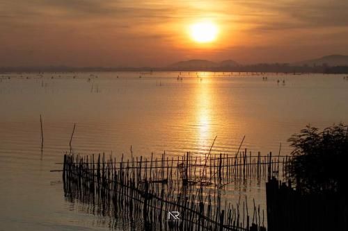 a large body of water with the sun setting at Touchwarin kohyor pool villa ธัชวารินเกาะยอพูลวิลล่า in Songkhla