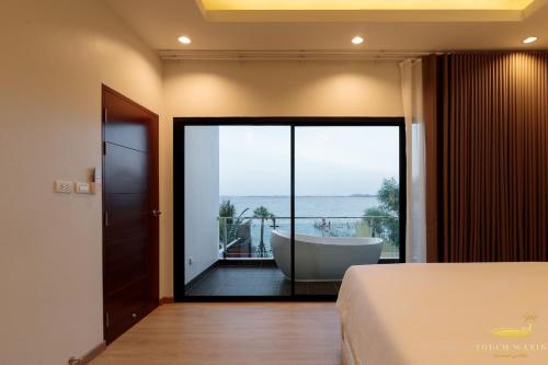 a bedroom with a view of a tub and a balcony at Touchwarin kohyor pool villa ธัชวารินเกาะยอพูลวิลล่า in Songkhla