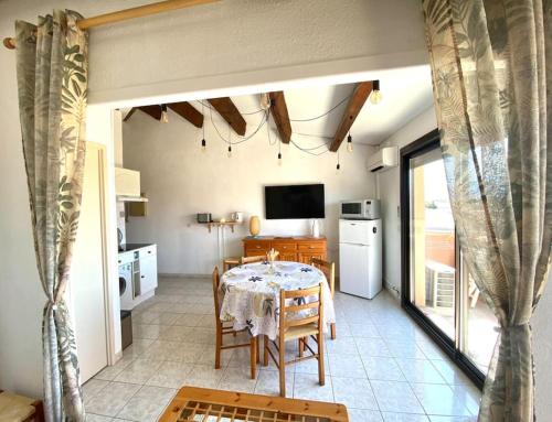 une cuisine et une salle à manger avec une table et une télévision dans l'établissement Appartement à proximité de la plage, à Saint-Cyprien