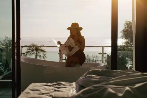 a woman sitting in a bath tub reading a book at Touchwarin kohyor pool villa ธัชวารินเกาะยอพูลวิลล่า in Songkhla