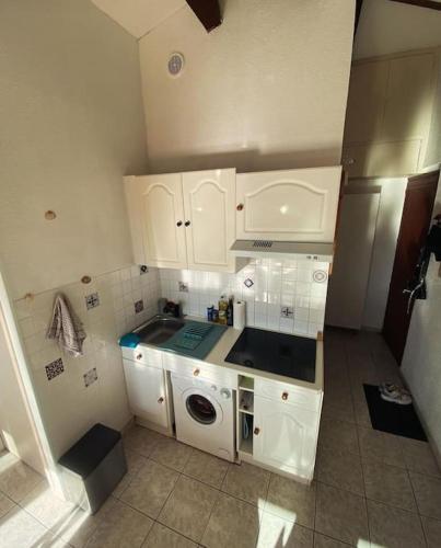 une petite cuisine avec des placards blancs et un lave-linge dans l'établissement Appartement à proximité de la plage, à Saint-Cyprien