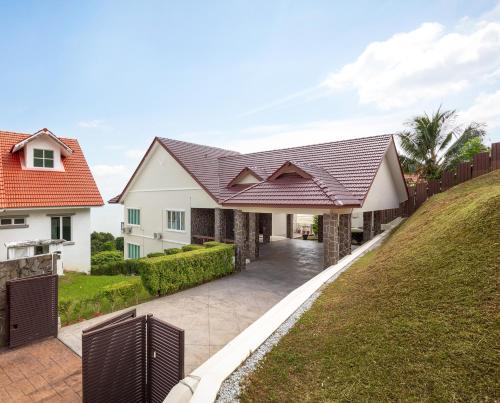 uma casa branca com um telhado castanho e uma entrada em Panoramic Seaview Holiday Home - Batu Ferringhi em Batu Ferringhi