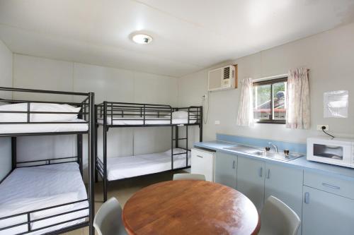 a room with three bunk beds and a wooden table at Discovery Parks - Mt Isa in Mount Isa